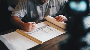 man designs blueprints on table